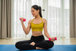 © Apiwan - Happy Asian young woman in sportswear sitting holding dumbbells to exercise for health care slim and body weight control at home.