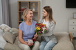© New Africa - Young daughter congratulating her mom with flowers at home. Happy Mother's Day