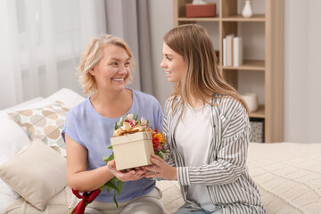 Wall Mural - Young daughter congratulating her mom with gift at home. Happy Mother's Day