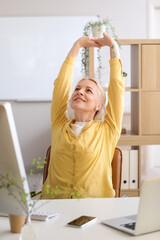 Mature female programmer working at table in office