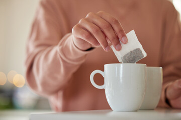 Canvas Print - Ending my day with a hot cup of tea. a woman dropping a tea bag into a waiting mug.