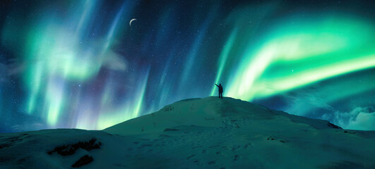 Wall Mural - aurora borealis glowing over silhouette hiker standing on the mountain in the night sky