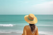 © dewaai - Back view of a woman wearing a hat sitting on a beach. Created with Generative AI Technology