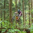 Spektakulärer Flug eines Mountainbikers über eine Rampe im Wald
