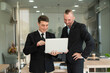 © ArLawKa - Two young businessmen looking at laptop smiling and expressing joy that the business succeeded according to their plans colleague talking to each other describing good partnership