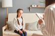 © sementsova321 - Smiling charming girl in psychologist office talking with doctor, schoolgirl patient psychotherapy consultation children trauma treatment professional help.