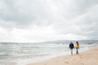 © Westend61 - Man and woman walking together on coastline at beach