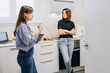 © Westend61 - Nutritionist explaining client standing with arms crossed in kitchen at home