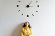 © Westend61 - Woman under large clock on wall