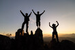 © Tinnakorn - Silhouette of happy teamwork with success gesture standing on the top of mountain, business teamwork concept, business victory, achieve business goal.