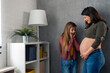 © Dorde - Thrilled little girl looking at mother's big round pregnant belly daydreaming about the baby sister feeling excited while standing together in living room at home.