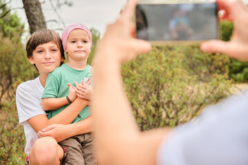 Child with pink headscarf taking a photo with his brother