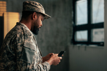 Soldier texting on mobile phone in office.