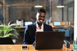 © JustLife - Portrait of successful businessman in office. Young smiling man using the laptop..