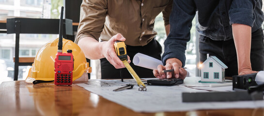 Wall Mural - Civil engineer teams meeting working together wear worker helmets hardhat on construction site in modern city. Foreman industry project manager engineer teamwork. Asian industry professional team.