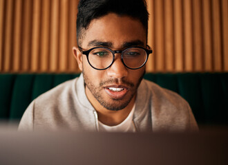 Poster - .. Closeup of geeky young indian man wearing glasses while reading something interesting and sitting inside. Man wearing glasses while reading online. Dedicated male student doing research in cafe.