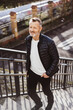© contrastwerkstatt - Smiling bestager man climbing up bridge stairs with hands in pockets