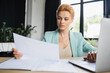 © LIGHTFIELD STUDIOS - focused redhead businesswoman working with blurred papers and laptop in office.