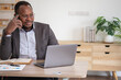 © PHAISITSAWAN - An African American businessman in a black suit uses a mobile phone to communicate with clients and a laptop to view company profits. to build confidence for customers to come and invest in the office