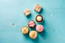 A Sweet Surprise: A Top View Flat Lay Of Cupcakes, Gifts, Coffee, And Gypsophila Flowers On A Pastel Blue Background.