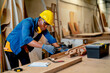 © narong - African American carpenter man hold and check tool for wood working and stay in factory workplace.