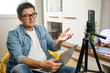 © Inna Vlasova - Hand free. Middle-aged male sitting at home before smartphone fixed on tripod. Video blogger recording content to channel. Young man making video stream