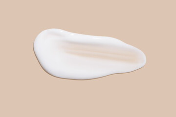 The flowing cream on a beige background. Smudged flowing smear of cosmetic cream.