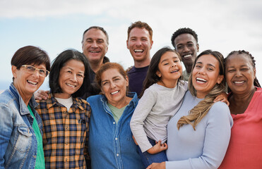 group of multigenerational people hugging each other while smiling on camera - multiracial friends h