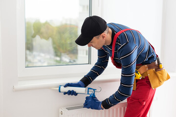 Wall Mural - Construction worker sealing window with caulk, closeup