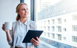© Michael C/peopleimages.com - A relaxing coffee break goes a real long way. Shot of a mature businesswoman looking out of a window while using a digital tablet and having coffee in a modern office.