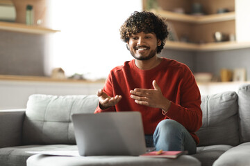 Sticker - Smiling young indian man making video call with laptop at home