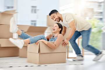 Caught up in a whirlwind of excitement. Shot of a young couple playing with boxes while moving house.