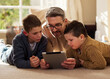 © Nina L/peopleimages.com - Dont tell mom I let you watch this. Shot of a father and sons using a digital tablet together at home.