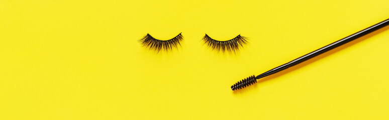 Wall Mural - Creative layout with eyelashes and brush mascara. Closed eyes on yellow background