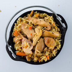 Sticker - Hot pilaf with chicken meat, carrots, tomatoes, onions and herbs in a cast iron pot.