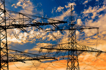 high voltage electric pylons against sky with dramatic clouds