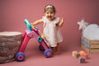 Bébé fille princesse souriante sur fond rose avec jouet