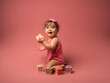 Bébé fille qui joue avec des cubes souriante sur fond rose