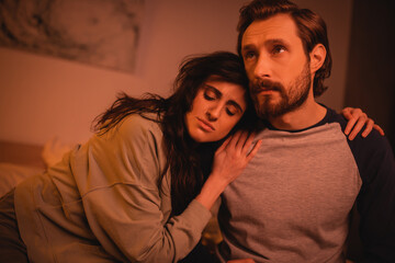 Wall Mural - Brunette woman hugging sad boyfriend in bedroom at night.