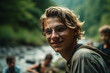 © wetzkaz - young adult man or teenager by a river or lake in the mountains with his friends in summer in sunshine. Generative AI