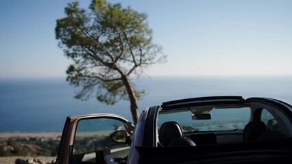 Wall Mural - Caucasian female arrived at beautiful place and gets out of car to admire sea view during travel. Eco vehicle and care for the environment. Young woman parked with scenery nature view enjoying tourism