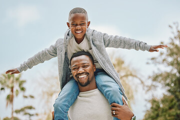 Best dad in the world. Cropped portrait of an adorable little boy sitting on his fathers shoulders outside.