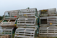 A Stack Of Lobster Pots Sits On A Local Wharf Out Of Water Waiting For The Lobster Fishing Season To Start. The Traps Are Filled With Weights And Licenses. Some Are Square And Some Are Round Shapes. 