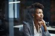 © Trinette Reed - Portrait of black business woman at work in office daydreaming shot through glass window. Generative AI.