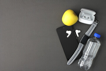 Items for exercising on a yoga mat such as headphones, cell phone, water, towel and apple for a healthy life and well-being