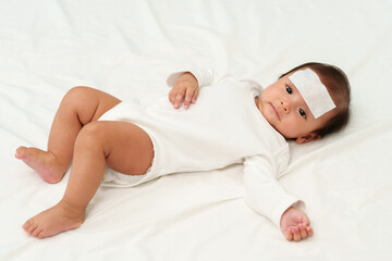 sick baby with cool fever jel pad on forehead
