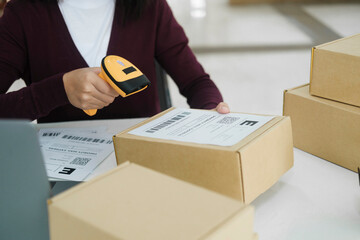 Female online business owner scan shipping label on parcel.