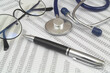 Documents with numbers, eyeglasses and stethoscope with pen close up.