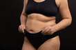 © Юля Бурмистрова - Overweight woman in black underwear pull up panties on belly. Flaunt figure imperfections, fat folds on body. Studio portrait over black background. Concept of obesity, body positive, self acceptance.