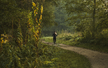 Canvas Print - Girl running in the park in the morning. Back view. Fit woman has her morning exrcise outdoor.